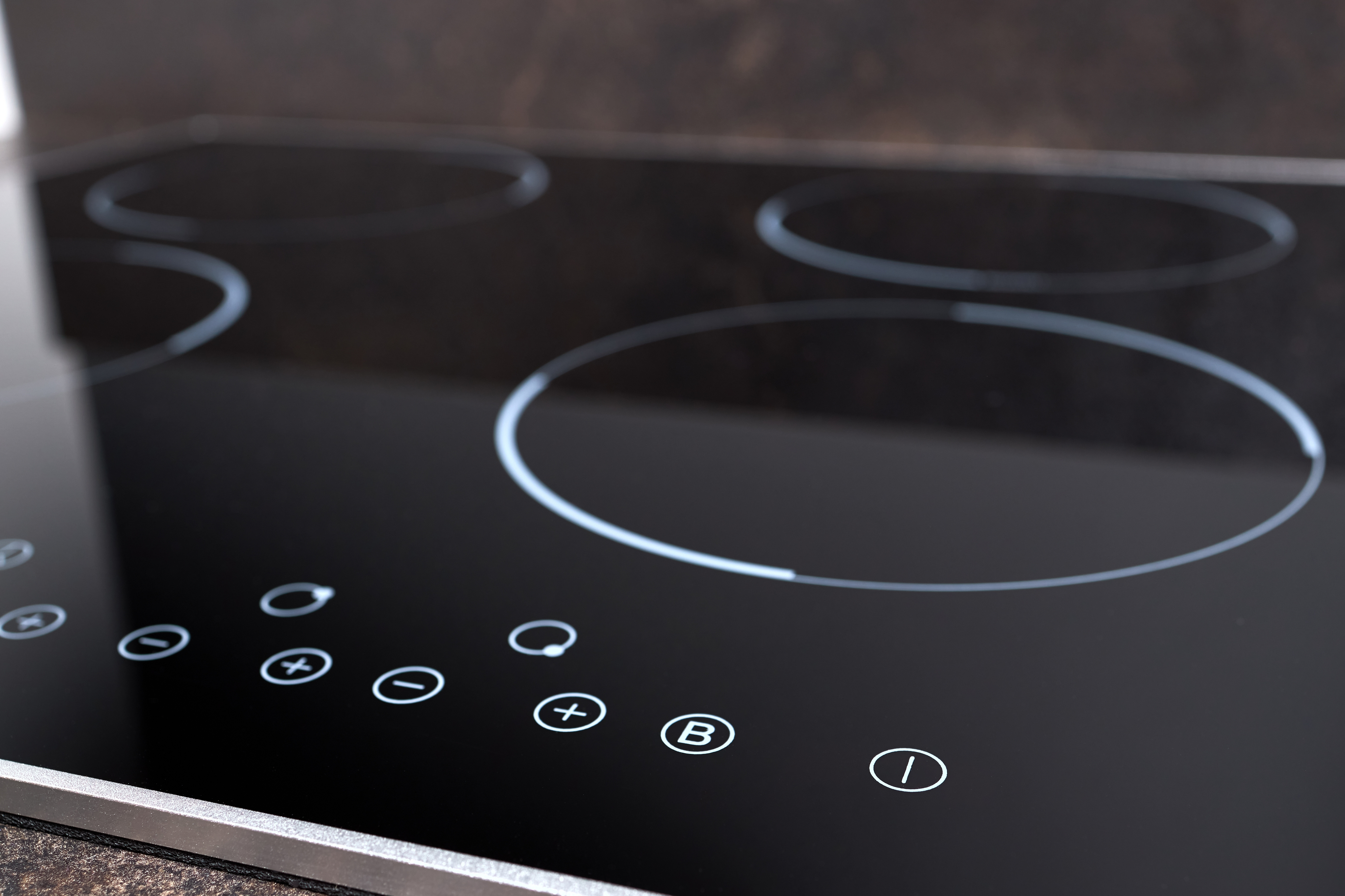 Close-up of a sleek black induction cooktop with touch controls.